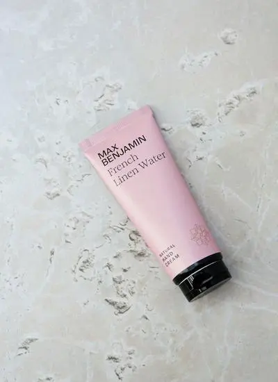 Product shot of Max Benjamin French Linen Water Hand Cream with marble stone in background.